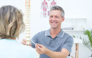 a chiropractor demonstrates a spine during a consultation