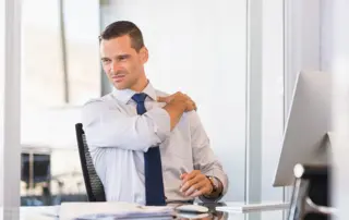 Young businessman at work suffering from shoulder pain.