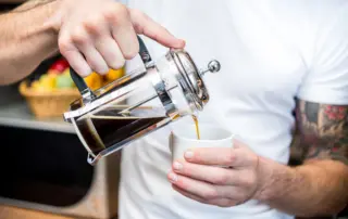 a man pours coffee for himself from a french press