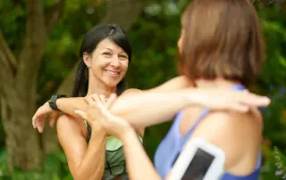 Two women stretching their shoulders before exercise