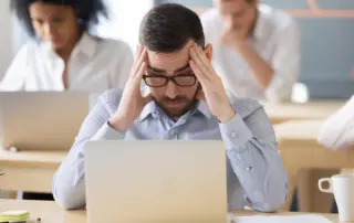 a stressed and tired man looks at his laptop