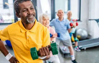 a elderly man lifts free weights at the gym