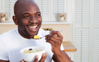 man smiling eating a bowl of fruit