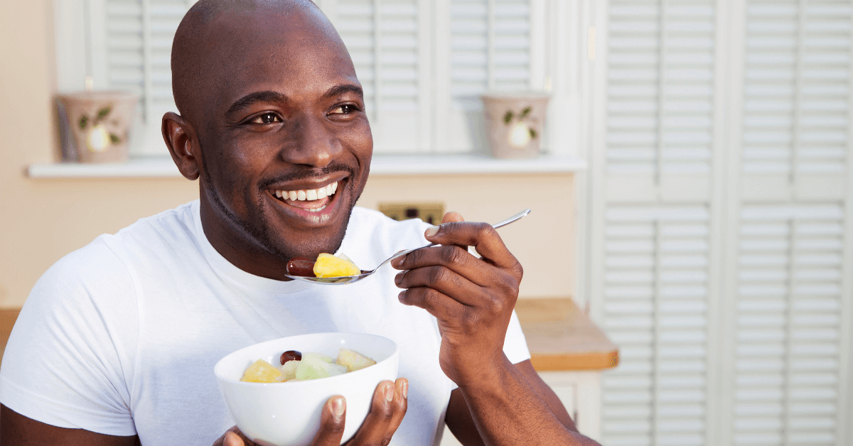 man smiling eating a bowl of fruit